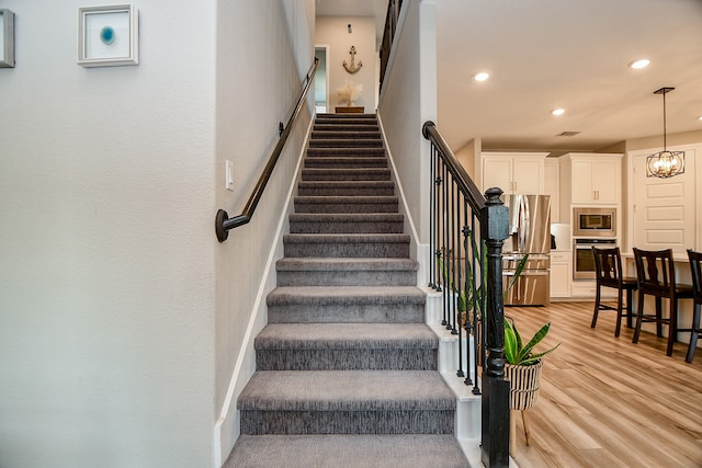 staircase featuring hardwood / wood-style floors and a chandelier