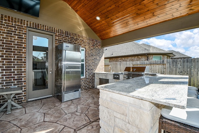 view of patio with area for grilling, an outdoor wet bar, and an outdoor kitchen