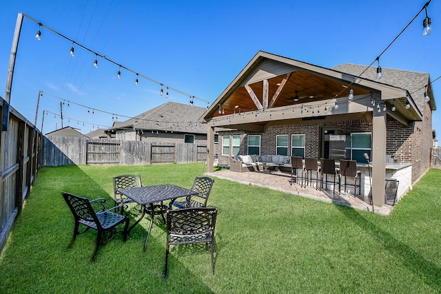 back of house with outdoor lounge area, ceiling fan, a yard, exterior bar, and a patio