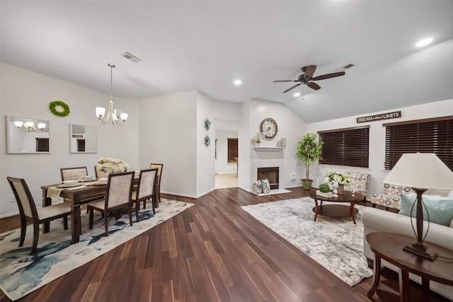 living room with ceiling fan with notable chandelier, dark wood-type flooring, and vaulted ceiling