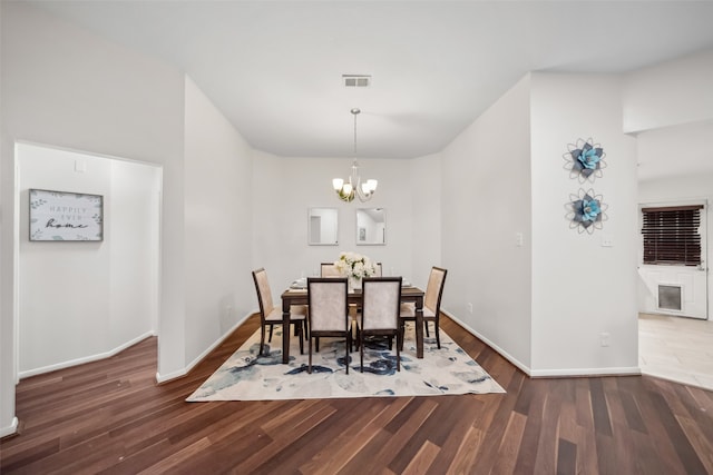 dining space featuring dark wood-type flooring and a notable chandelier