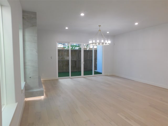 spare room featuring light wood-type flooring and a notable chandelier