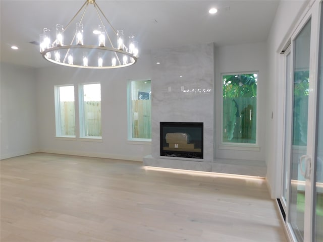 unfurnished living room with a fireplace, light hardwood / wood-style floors, and a notable chandelier