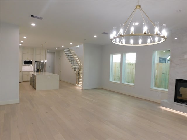 unfurnished living room with a large fireplace and light wood-type flooring