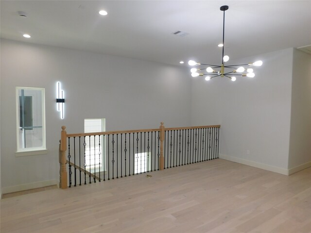 empty room featuring light hardwood / wood-style floors and a notable chandelier