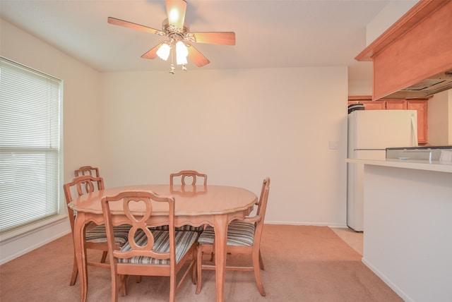 dining area featuring ceiling fan and light carpet