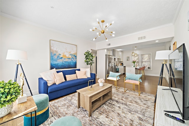 living room with hardwood / wood-style floors, crown molding, and a notable chandelier