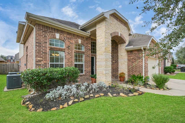 view of front of house featuring a front yard, a garage, and central AC unit