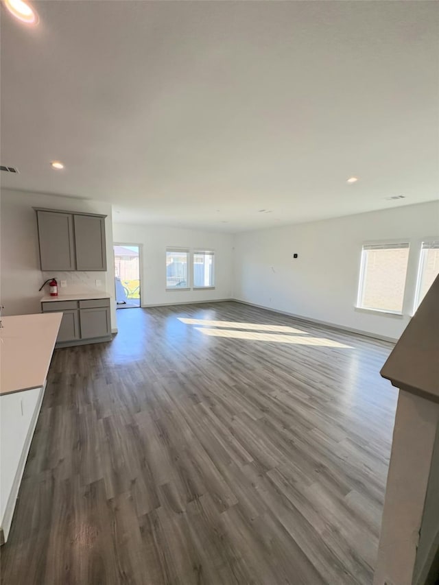 unfurnished living room featuring dark wood-type flooring and a healthy amount of sunlight