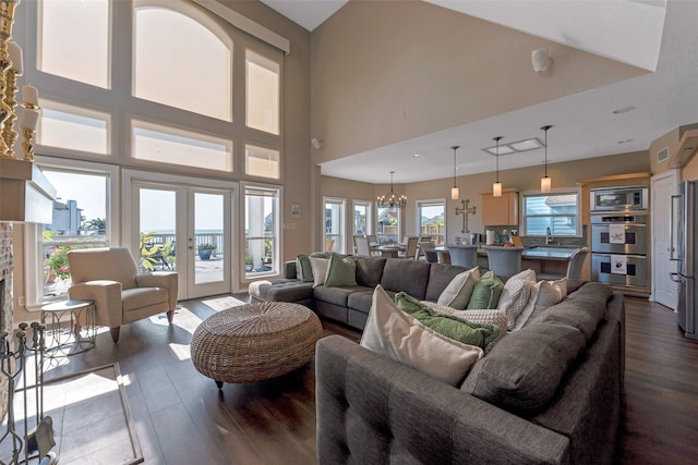 living room with french doors, sink, a high ceiling, hardwood / wood-style floors, and a chandelier