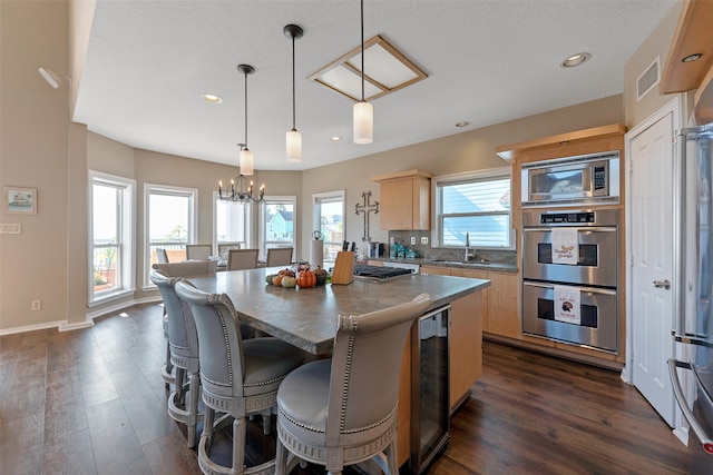 kitchen featuring hanging light fixtures, appliances with stainless steel finishes, a center island, and a wealth of natural light