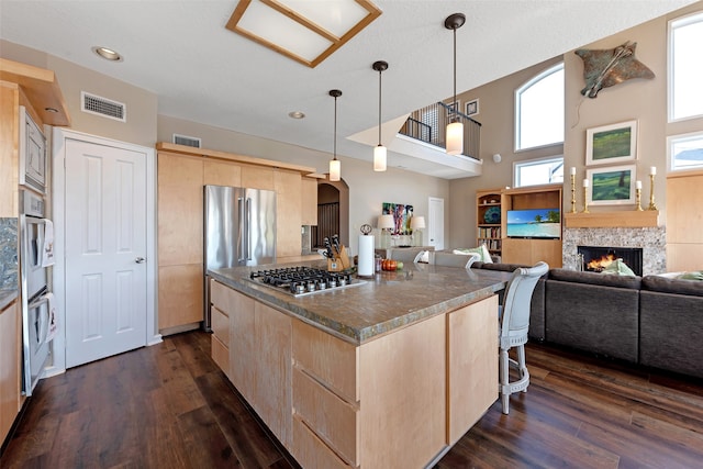 kitchen featuring dark hardwood / wood-style floors, light brown cabinets, stainless steel appliances, and hanging light fixtures