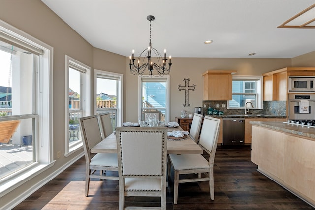 dining room with sink, dark wood-type flooring, and an inviting chandelier