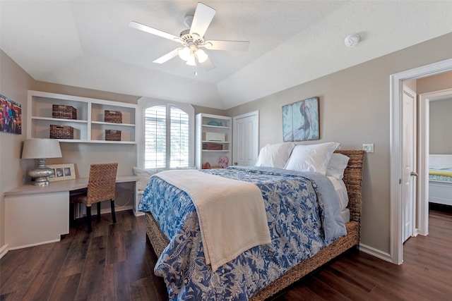 bedroom featuring a raised ceiling, ceiling fan, built in desk, dark hardwood / wood-style flooring, and a closet