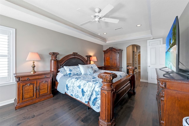 bedroom featuring a raised ceiling, ceiling fan, and dark hardwood / wood-style floors