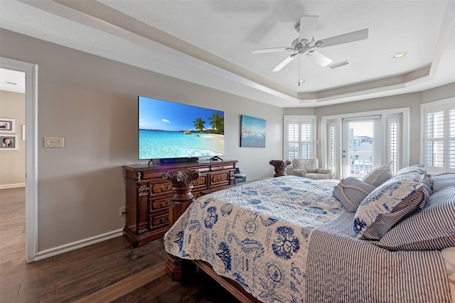 bedroom with access to outside, ceiling fan, a tray ceiling, and dark wood-type flooring