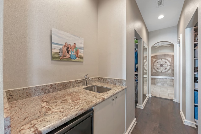 interior space featuring sink, light stone countertops, and dark wood-type flooring