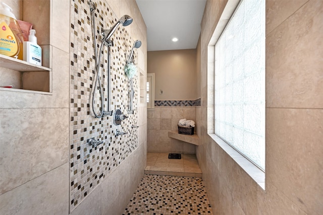 bathroom featuring tile patterned flooring, a tile shower, and tile walls