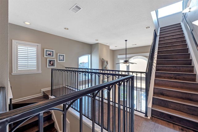 stairs featuring hardwood / wood-style floors, ceiling fan, and a healthy amount of sunlight