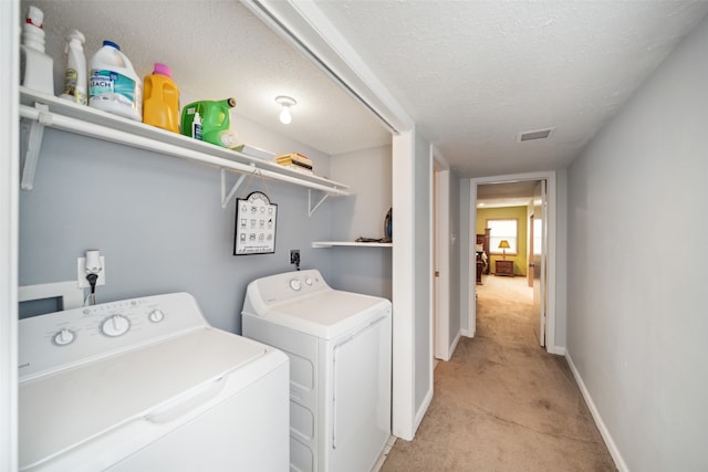 laundry room featuring light carpet, a textured ceiling, and washing machine and dryer