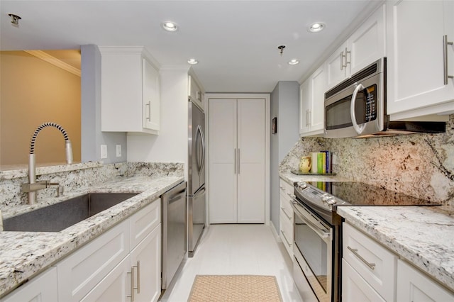 kitchen featuring tasteful backsplash, light stone counters, stainless steel appliances, sink, and white cabinets