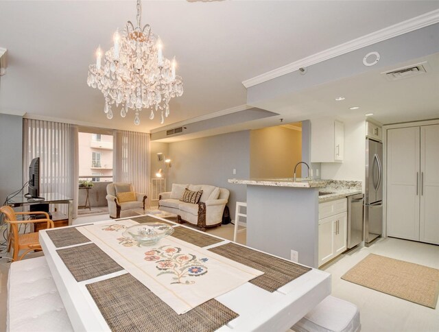 dining space featuring crown molding, sink, and an inviting chandelier