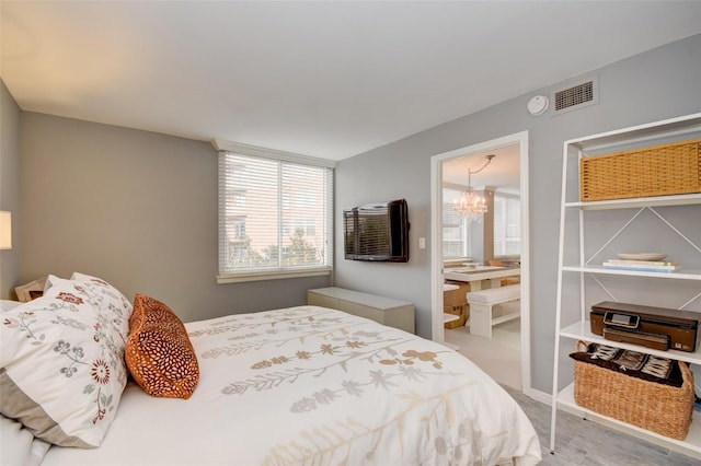 bedroom with a chandelier and light wood-type flooring