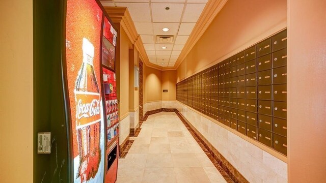 interior space with tile patterned flooring, mail boxes, crown molding, and a paneled ceiling