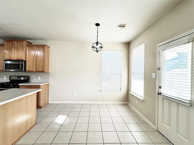 kitchen featuring pendant lighting, decorative backsplash, gas stove, and light tile patterned floors