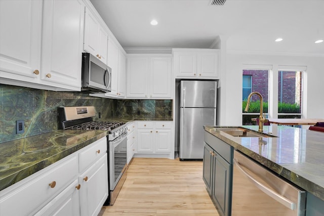 kitchen with decorative backsplash, stainless steel appliances, sink, white cabinets, and light hardwood / wood-style floors