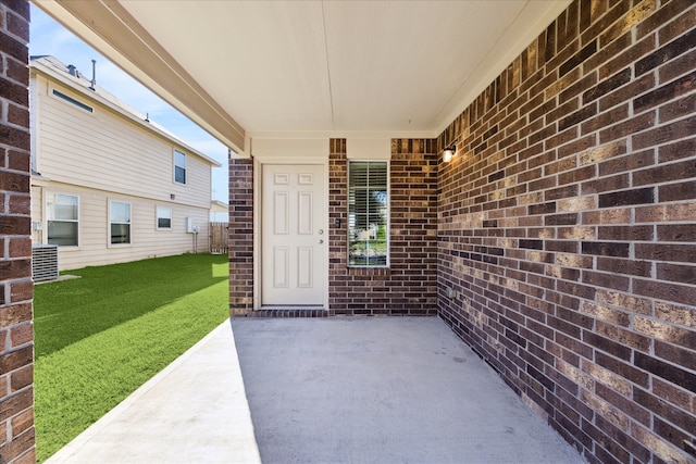 property entrance with a lawn, a patio, and central AC unit