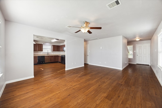 unfurnished living room with ceiling fan, sink, and dark wood-type flooring