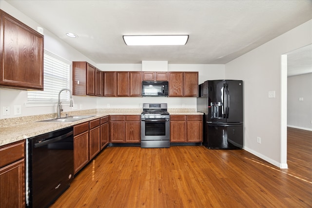 kitchen featuring wood-type flooring, sink, and black appliances