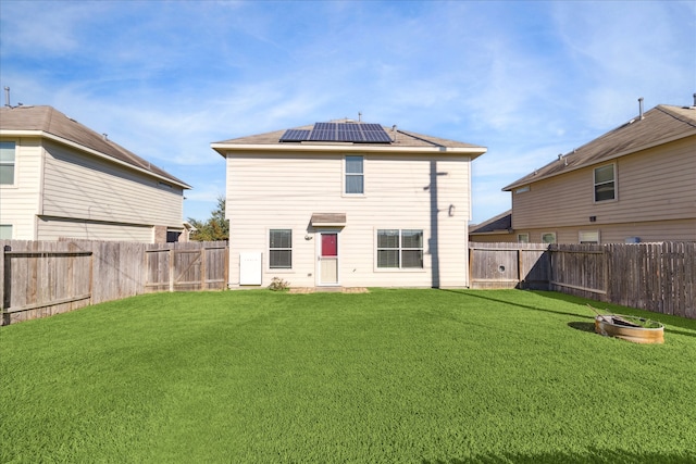 rear view of house featuring a lawn and solar panels