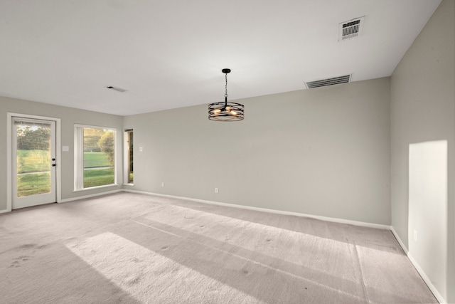 spare room featuring light colored carpet and an inviting chandelier