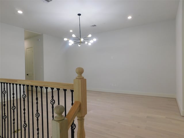 hallway featuring light wood-type flooring and an inviting chandelier