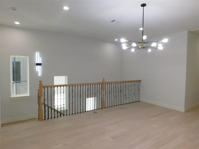 spare room featuring a chandelier and light hardwood / wood-style floors