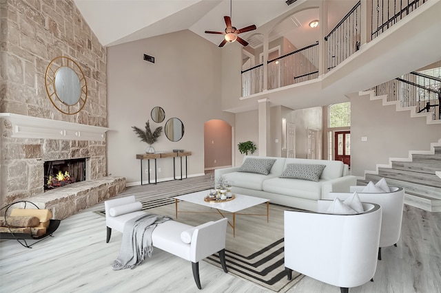 living room with ceiling fan, light hardwood / wood-style floors, a fireplace, and high vaulted ceiling