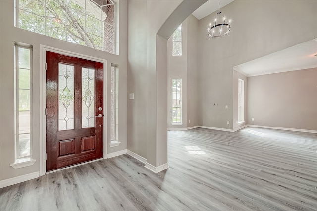 foyer with a towering ceiling, a healthy amount of sunlight, and light wood-type flooring