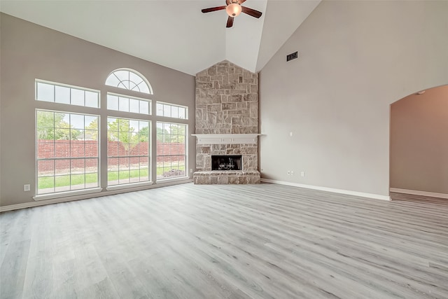 unfurnished living room with a fireplace, light wood-type flooring, high vaulted ceiling, and ceiling fan