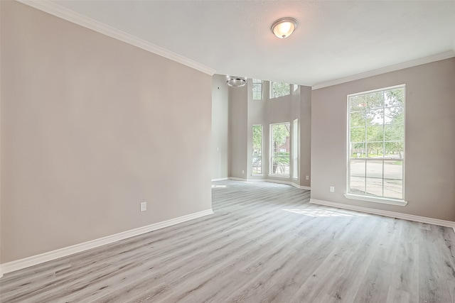 spare room with ornamental molding, a wealth of natural light, and light hardwood / wood-style flooring