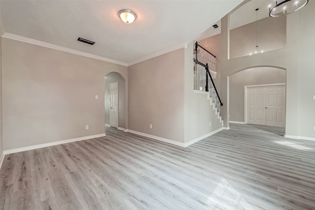 unfurnished room with light wood-type flooring, high vaulted ceiling, and crown molding