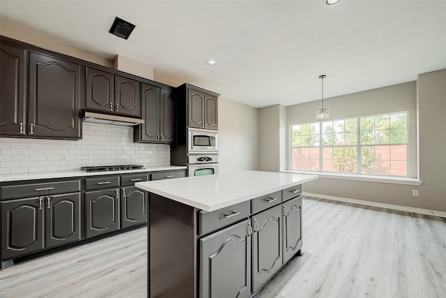 kitchen featuring a center island, light hardwood / wood-style flooring, tasteful backsplash, dark brown cabinetry, and stainless steel appliances