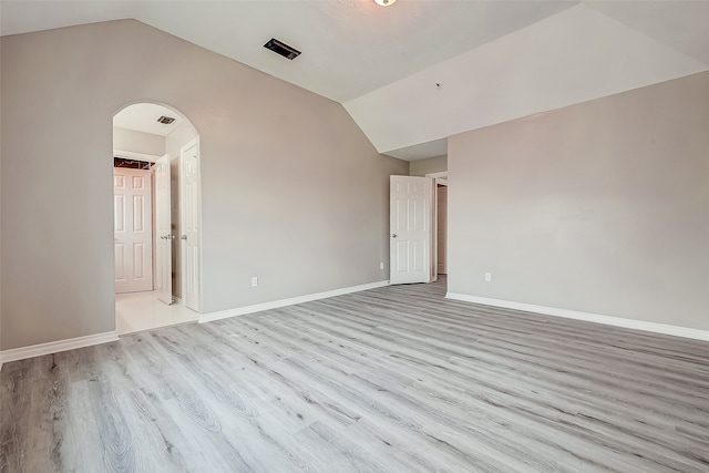 spare room with light hardwood / wood-style flooring and vaulted ceiling