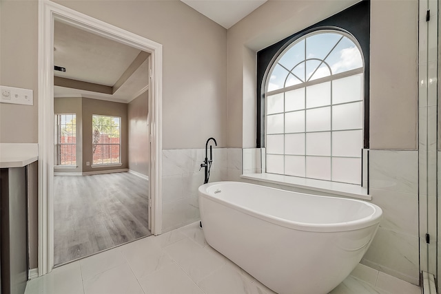 bathroom with a tub, tile walls, and hardwood / wood-style flooring