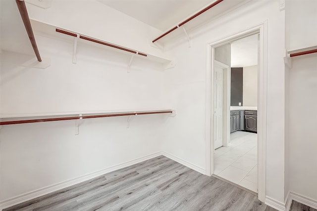 walk in closet with light hardwood / wood-style floors