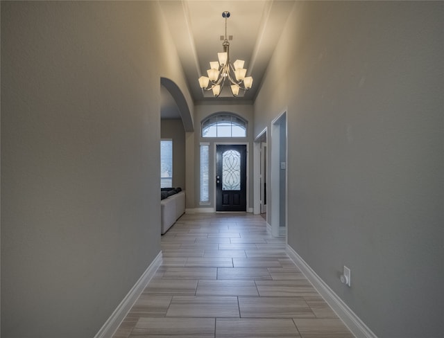 foyer entrance with light wood-type flooring, high vaulted ceiling, and a notable chandelier