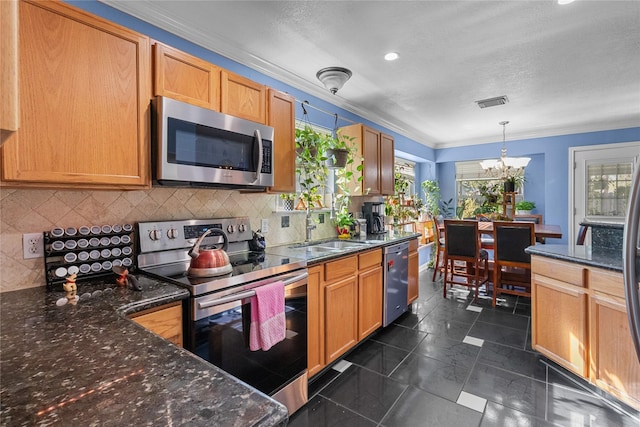 kitchen with sink, stainless steel appliances, a notable chandelier, dark stone countertops, and pendant lighting