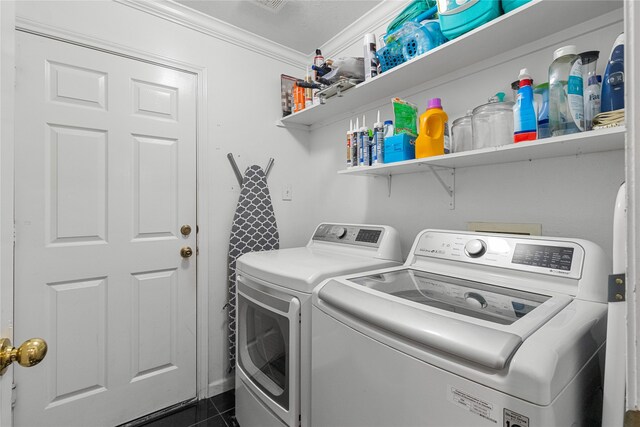 laundry room with washing machine and clothes dryer, dark tile patterned floors, and ornamental molding