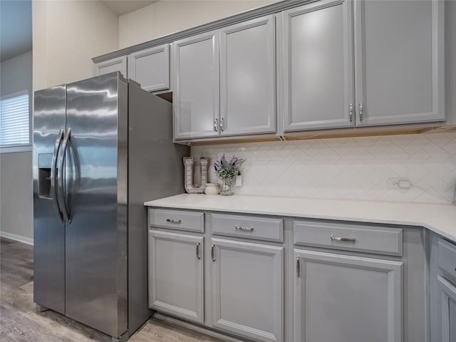 kitchen with decorative backsplash, stainless steel fridge, light hardwood / wood-style floors, and gray cabinetry